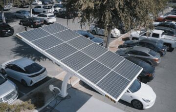 Electric cars charging at a solar-powered station in a parking lot.